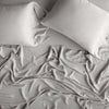 Madera Luxe fitted sheet, shown with matching rumpled flat sheet and sleeping pillows - fog, overhead view.