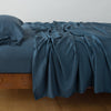 Madera Luxe Fitted Sheet | Midnight | fitted sheet with matching rumpled flat sheet and sleeping pillow - side view.