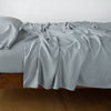 Madera Luxe fitted sheet with matching rumpled flat sheet and sleeping pillow - mineral, side view.