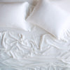 Madera Luxe Twin Fitted Sheets | White | rumpled sheeting and sleeping pillows - overhead view.