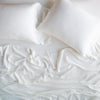 Madera Luxe Twin Fitted Sheets | Winter White | rumpled sheeting and sleeping pillows - overhead view.