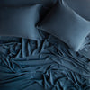 Madera Luxe Flat Sheet | Midnight | Rumpled sheeting, shown with matching sleeping pillows - overhead view.