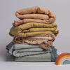 Mirabella Baby Blanket — Limited Release | a stack of silk and tencel™ baby blankets shown in pastel rainbow colors with  a set of toy blocks as a rainbow.
