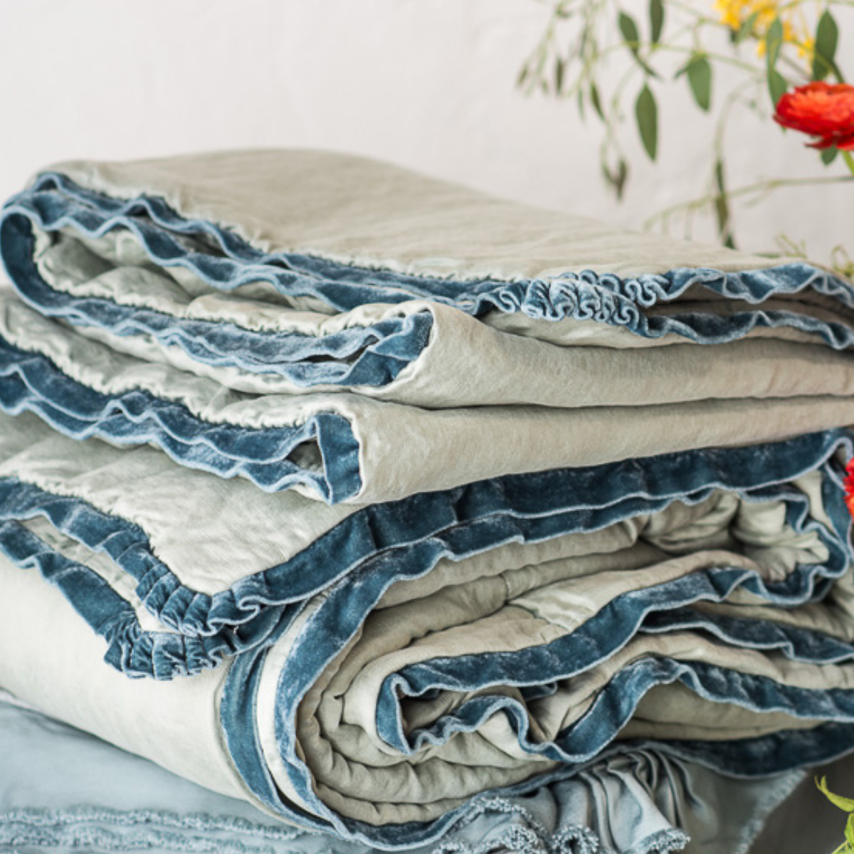Paloma Blanket | Close-up of Paloma throw blanket in mineral, neatly folded, highlighting the richly dyed silk velvet trim.