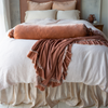 Paloma bed skirt and matching shams add subtle shine to linen and cotton bedding accented with ruffled silk velvet, all in pink and cream tones - end of bed view.