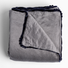Paloma Blanket | French Lavender | charmeuse blanket with silk velvet trim folded with a corner folded back to show trim contrast - shot overhead against a white background.