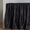 Paloma Crib Skirt | Midnight | charmeuse crib skirt shown on a white crib against a white wall and medium wood floor.