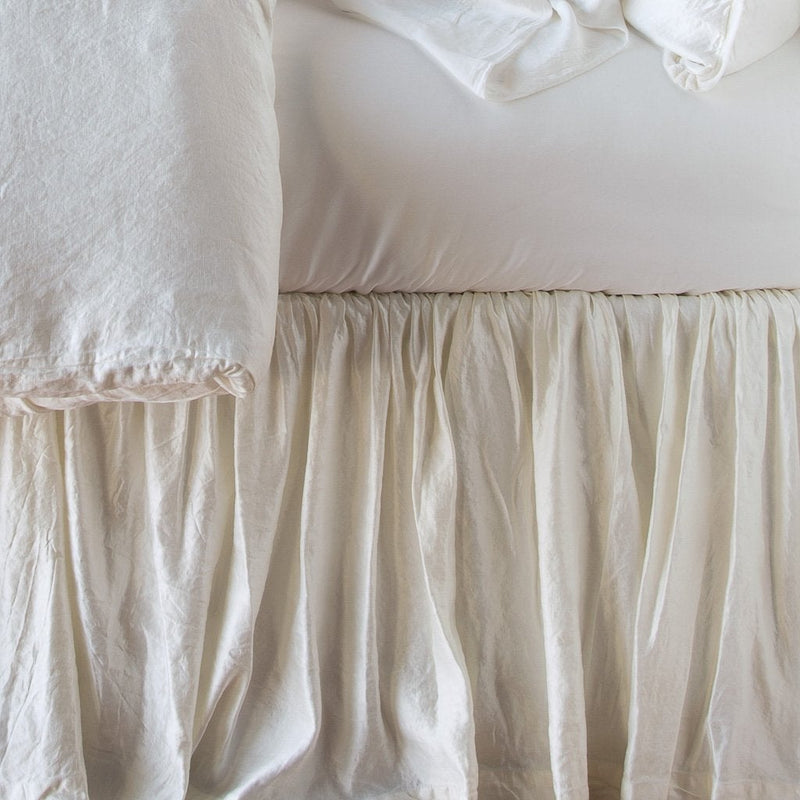 Close up of Paloma bed skirt, highlighting the shimmering fabric and the gathering detail - winter white, side view.