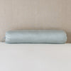 Paloma Throw Pillow | Mineral | Paloma bolster against white sheets against a neutral headboard - mineral.