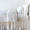 Paloma Duvet Cover | Winter White | duvet cover with matching pillows and bed skirt - side view.