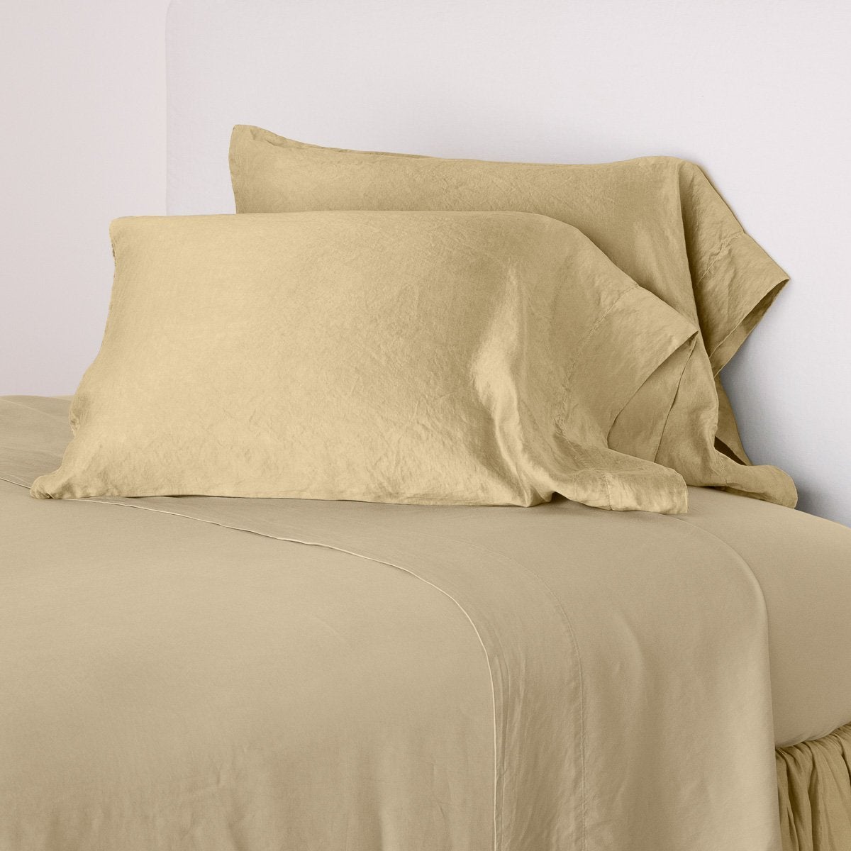 Paloma Pillowcase (Single) | Honeycomb | sleeping pillows leaning upright against a white wall on monochromatic sheeting - cropped three-quarter angle.