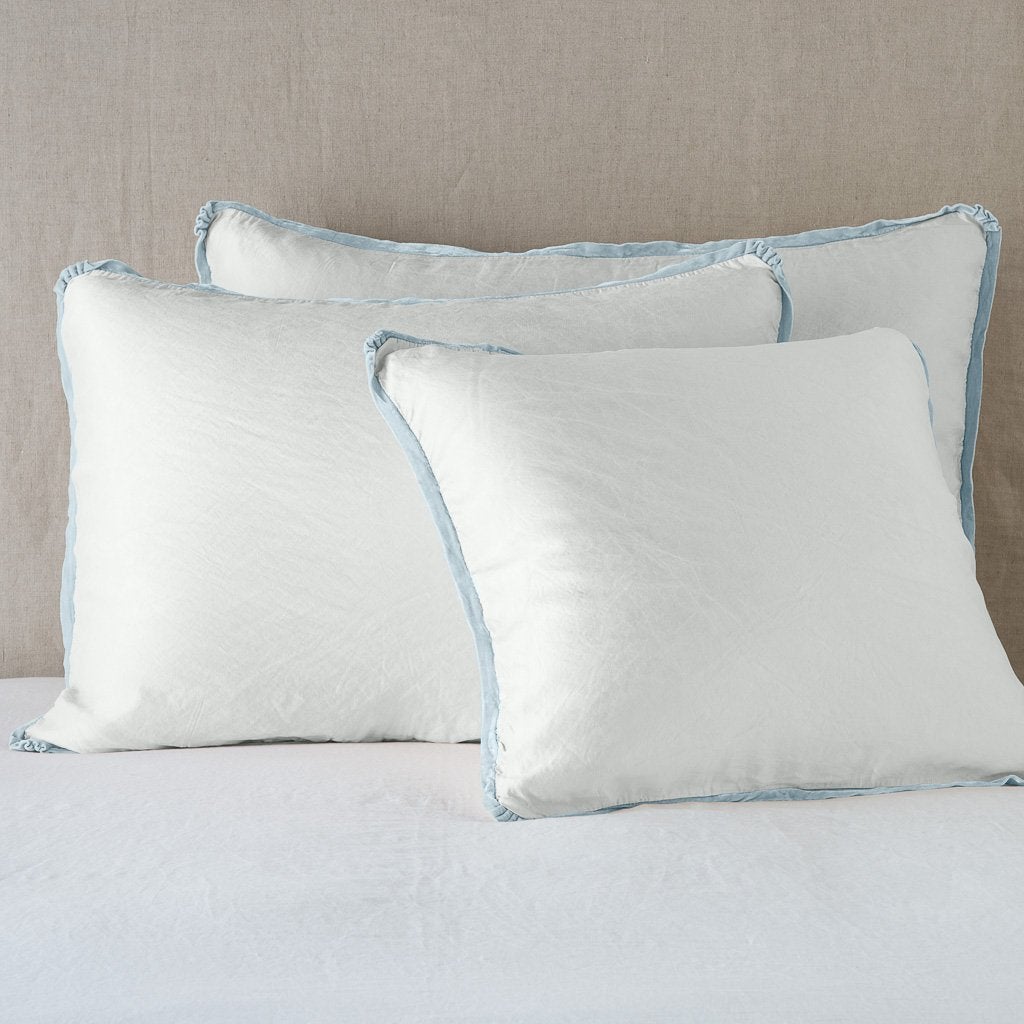 Paloma Sham | Cloud | shams leaning upright on white sheeting against a neutral headboard.