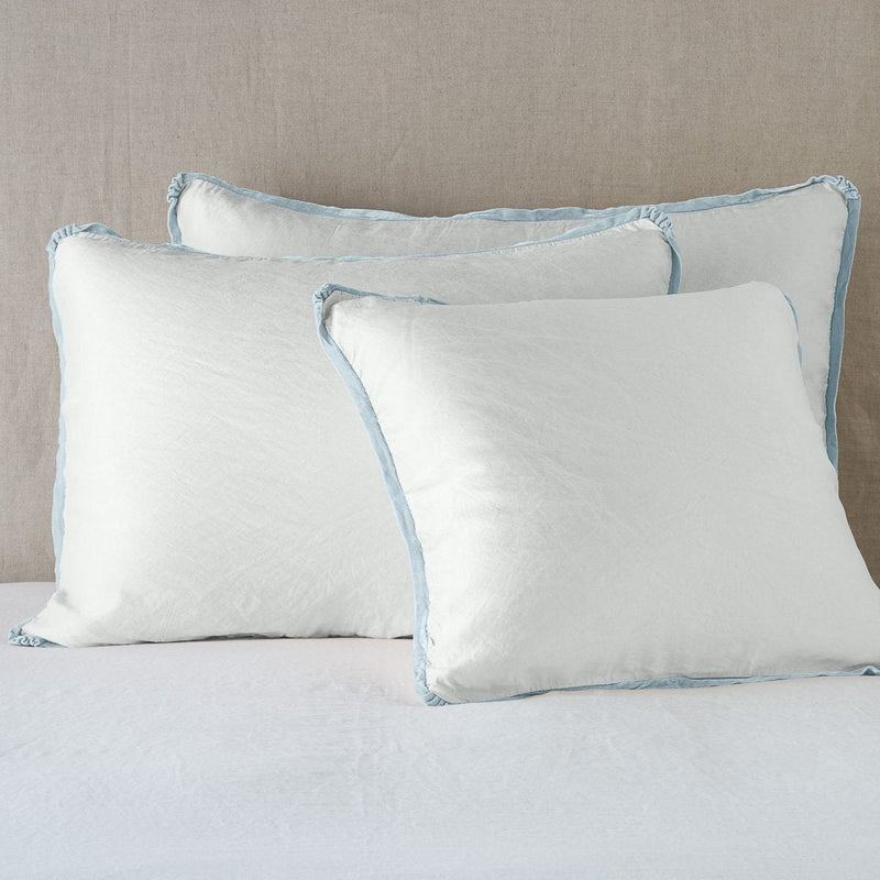 Paloma Sham | Cloud | shams leaning upright on white sheeting against a neutral headboard.