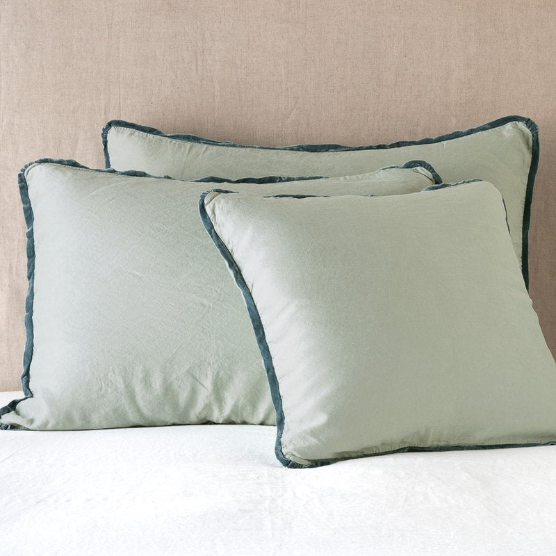 Paloma Sham | Eucalyptus | shams leaning upright on white sheeting against a neutral headboard.
