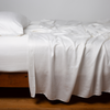 Seraphina Pillowcase (Single) | White | sleeping pillow, shown with matching rumpled sheets - side view.