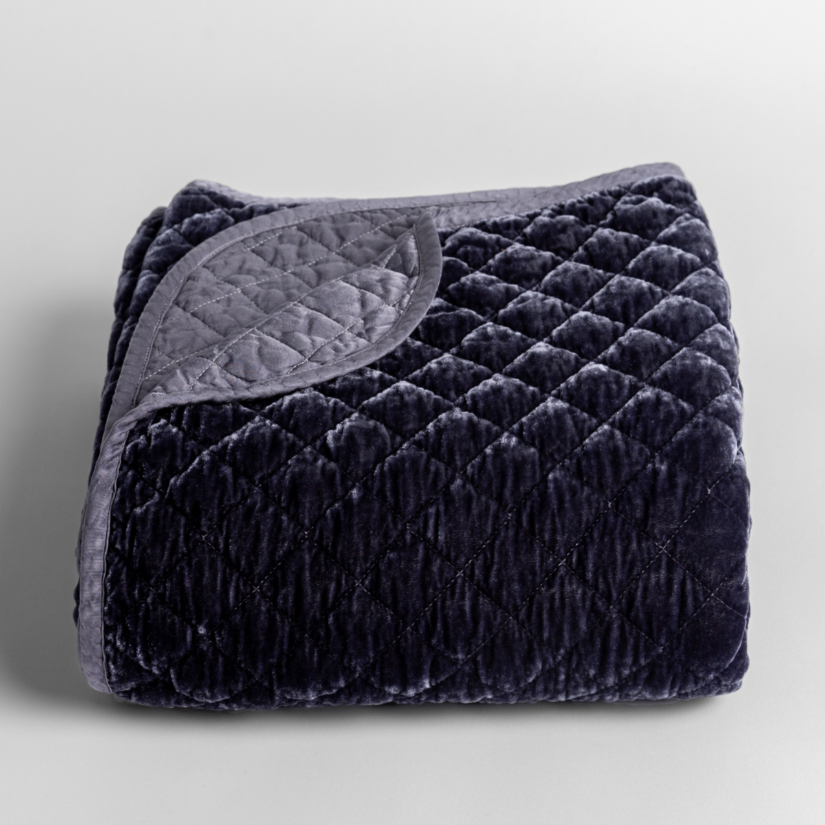 Silk Velvet Quilted Baby Blanket | French Lavender | quilted silk velvet quilted blanket folded with its corner folded back to reveal a satin back and binding.