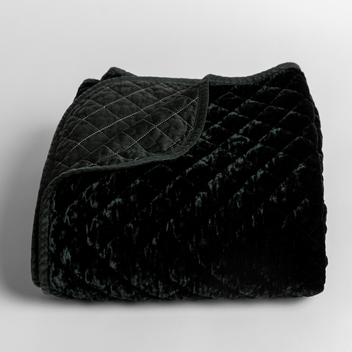 Silk Velvet Quilted Baby Blanket | Juniper | quilted silk velvet quilted blanket folded with a corner folded back to reveal its satin back and binding.