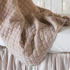 Pearl | Close up of silk velvet quilted baby blanket in pearl, draped over a monochromatic crib, showcasing the satin edge trim.