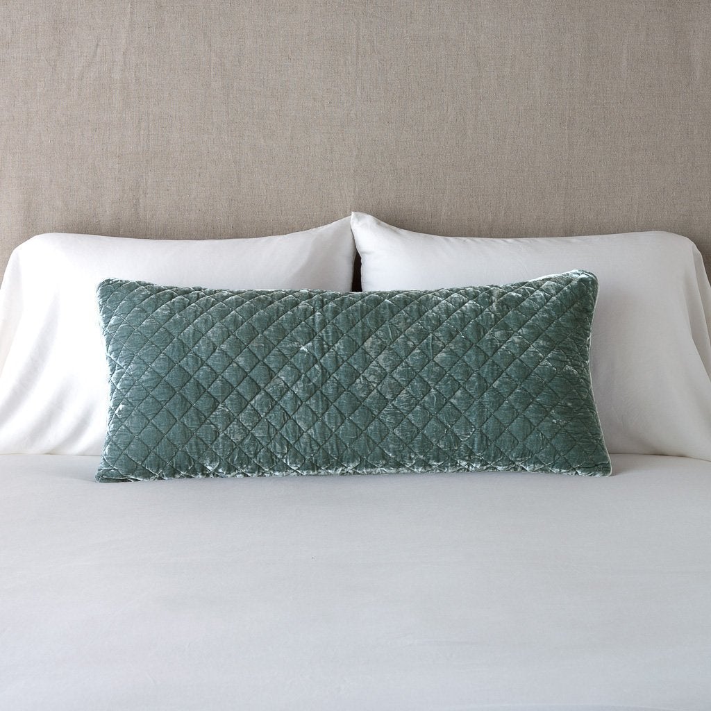 Silk Velvet Quilted Throw Pillow | Eucalyptus | 16x36 pillow leaning upright against white sleeping pillows and a neutral headboard.