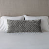 Silk Velvet Quilted Throw Pillow | Fog | 16x36 pillow leaning upright against white sleeping pillows and a neutral headboard.