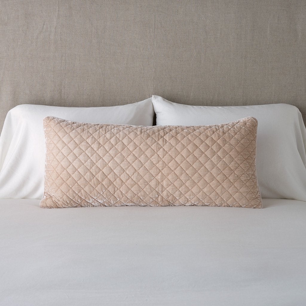 Silk Velvet Quilted Throw Pillow | Pearl | 16x36 pillow leaning upright against white sleeping pillows and a neutral headboard.