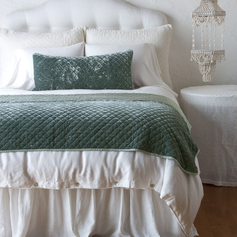 Silk Velvet Quilted Blanket | Eucalyptus | throw blanket and matching lumbar pillow on a neatly made white bed - end of bed view.