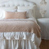 Silk Velvet Quilted Blanket | Pearl | throw blanket and matching lumbar pillow on a neatly made white bed - end of bed view.