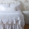 Silk Velvet Quilted Blanket | White | throw blanket and matching lumbar pillow on a neatly made white bed - end of bed view.