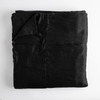 Taline Blanket | Corvino | folded bed blanket with corner folded downward showing linen back and tassel - overhead on white background.