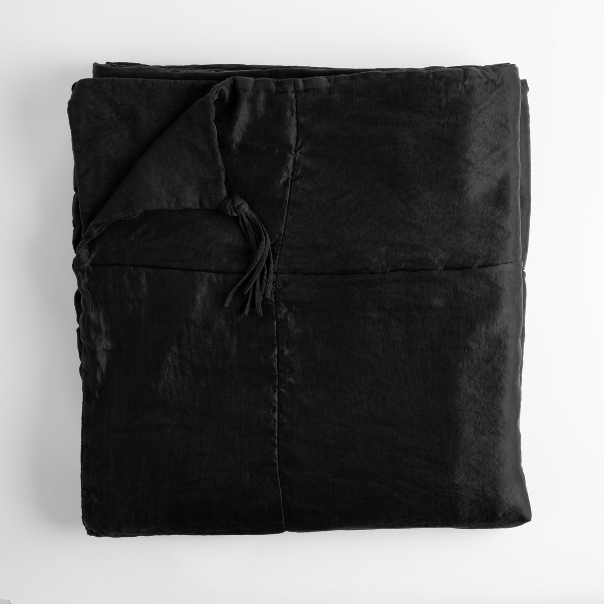 Taline Blanket | Corvino | folded bed blanket with corner folded downward showing linen back and tassel - overhead on white background.