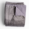 Taline Blanket | French Lavender | a folded charmeuse blanket with its corner pulled back to reveal its midweight linen back and charmeuse tassel.