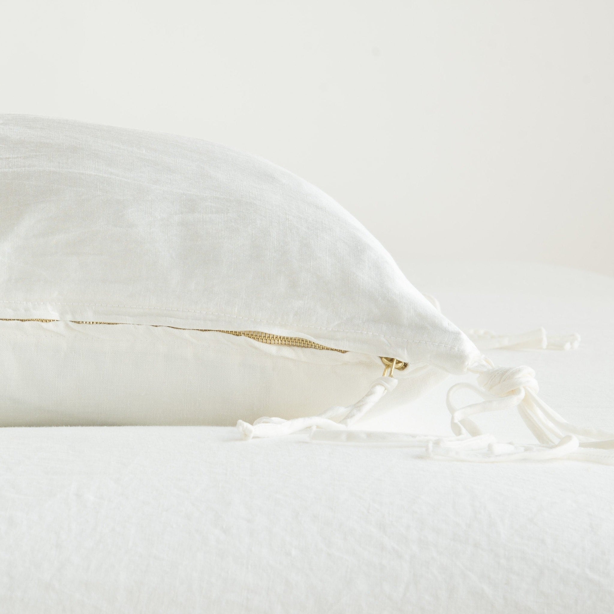 Taline Throw Pillow | Winter White | Close-up side vew featuring brass zipper with charmeuse pull and linen back.