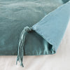 Taline Blanket | Cenote | Close up of blanket, with a corner turned back to showcase the midweight linen back and corner tassel - overhead view.