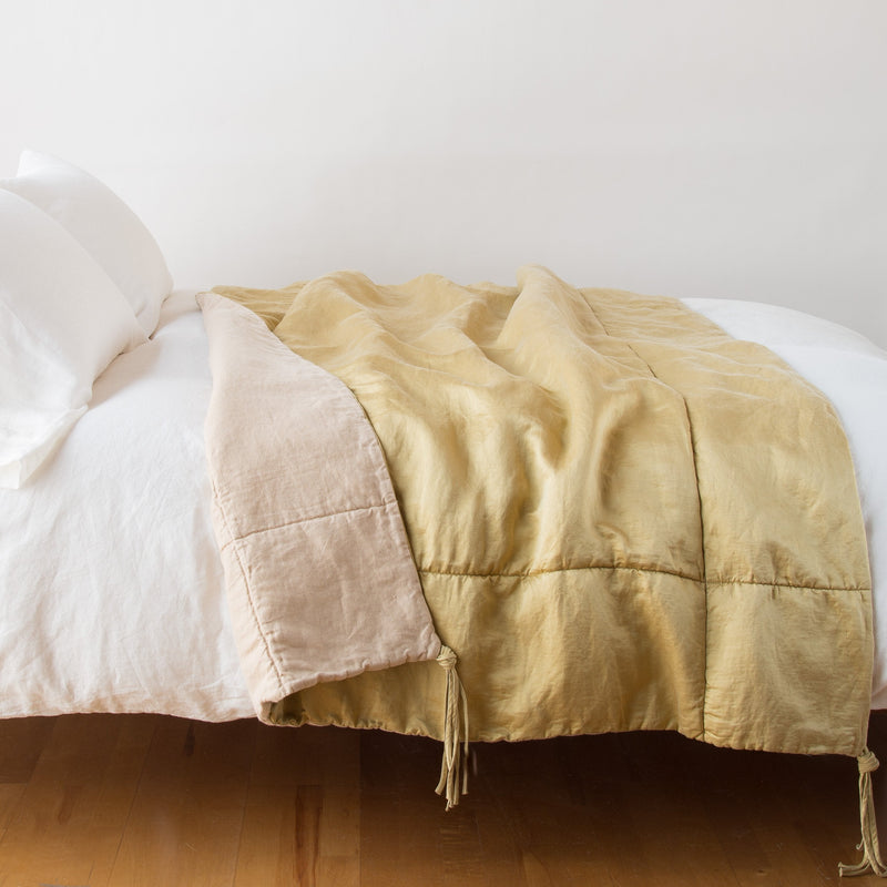 Taline Blanket | Honeycomb | blanket draped over a white bed, folded back to reveal midweight linen back - side view.