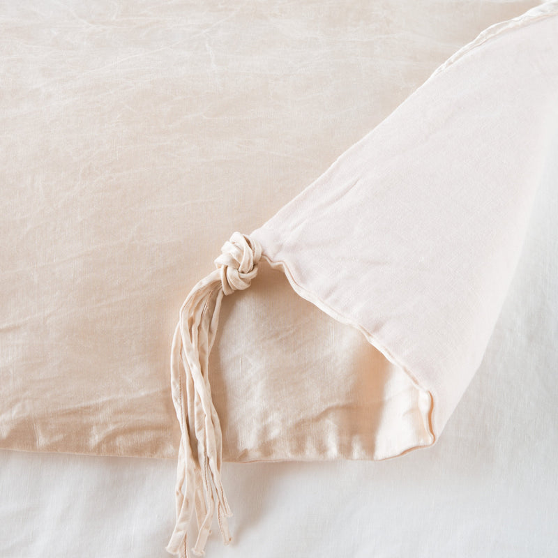 Taline Blanket | Pearl | Close up of blanket, with a corner turned back to showcase the midweight linen back and corner tassel - overhead view.