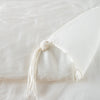 Taline Blanket | Winter White | Close up of blanket, with a corner turned back to showcase the midweight linen back and corner tassel - overhead view.