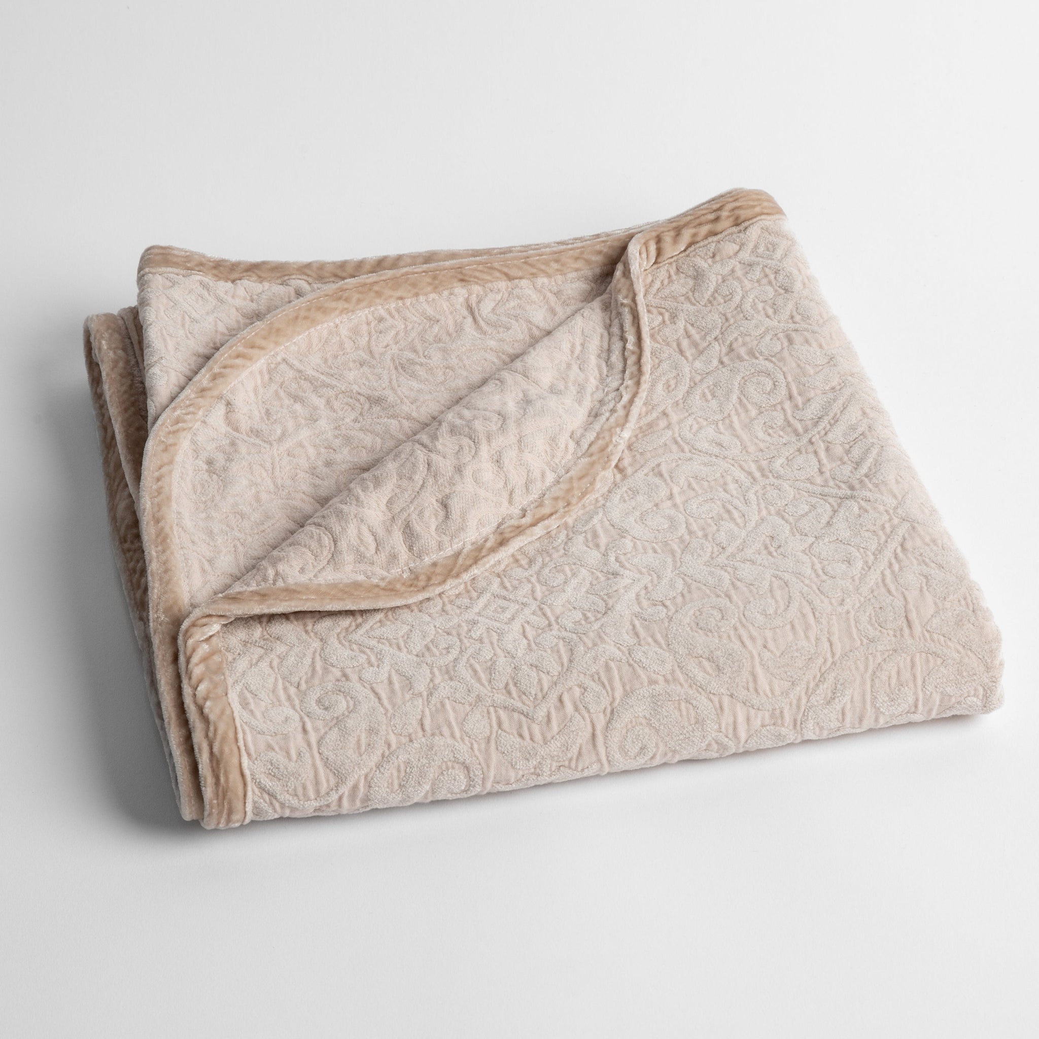 Vienna Baby Blanket | Pearl | a folded cotton chenille baby blanket trimmed in silk velvet shot overhead at a slight angle against a white background.