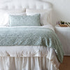 Vienna Throw Pillow | Vienna 16x36 pillow and matching throw blanket on a white, neatly made bed - eucalyptus, end of bed view.