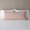 Vienna Throw Pillow | Rouge | 16x36 pillow leaning upright against white sleeping pillows on a neutral headboard.